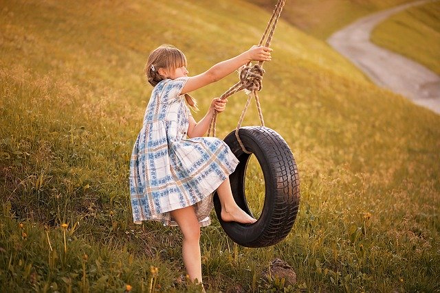 malá holčička houpající se na pneumatice